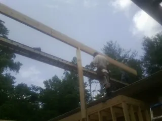 Carpenter setting a ridge beam over a new addition frame — Ice Dam Removal by Roofing Brothers in Asher