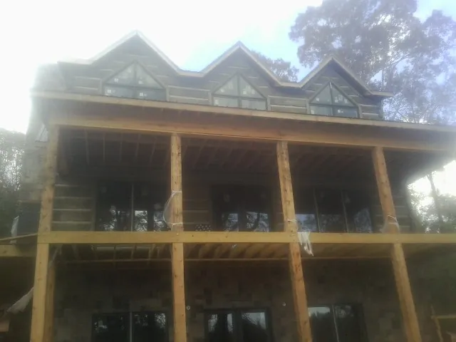 Dormers and porch framing on a large log home under construction — Roof Coating work by our crew in Asher