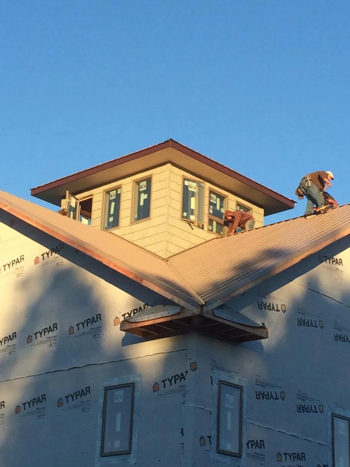 Roofers working around a rooftop cupola on a new metal roof at sunset — Roof Waterproofing in Asher by Roofing Brothers
